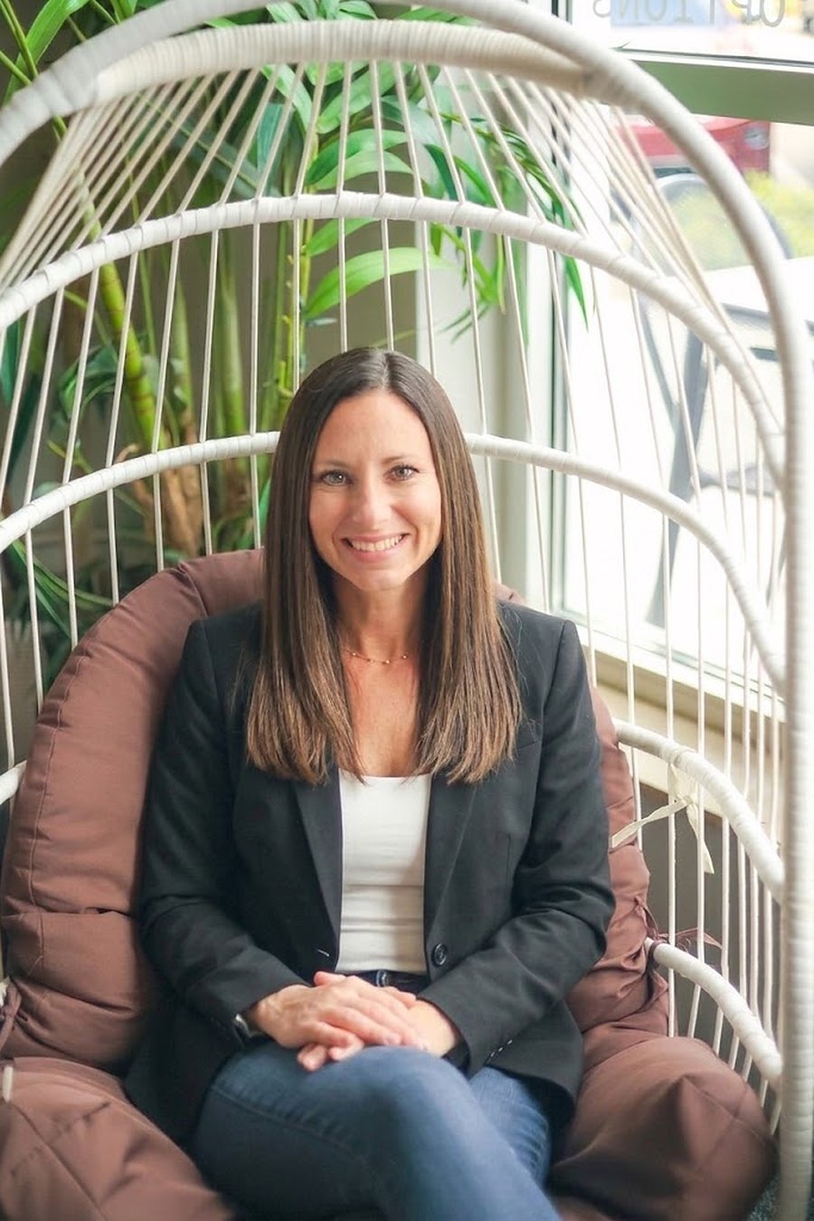 Julie Giancola smiling in a hanging chair at a Sarasota cafe