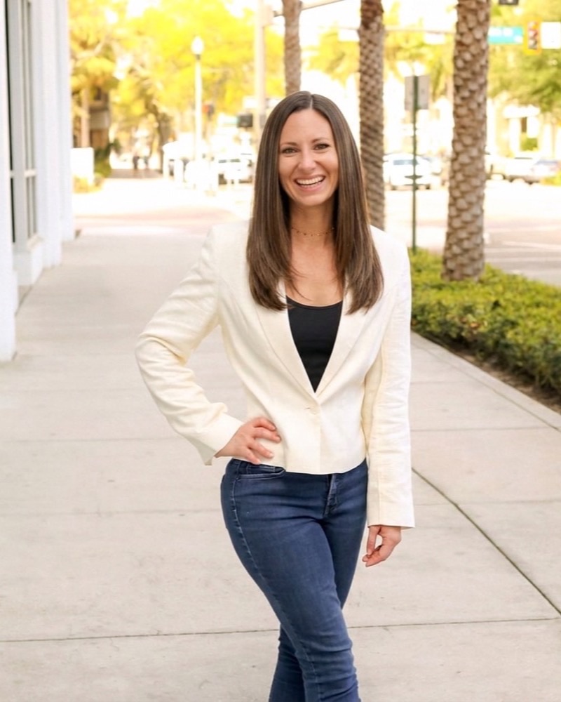 Julie Giancola smiling on a palm-lined sidewalk in downtown Sarasota