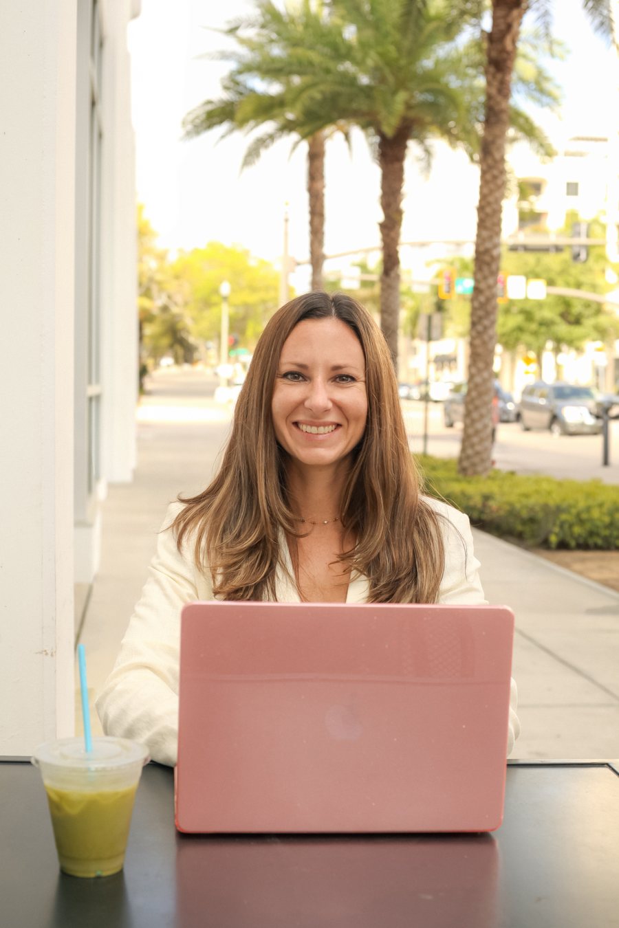 Julie Giancola smiling at her laptop in a Sarasota cafe